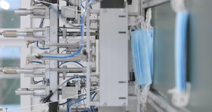 Vertical video. Manufacture of surgery masks. Medical mask on conveyor belt in the workshop of medical clothing factory. Production of disposable medical clothing for protection against the virus.