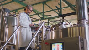Quality expert in a white lab coat working in a milk factory. Milk factory interior with big vats. Milk factory equipment.