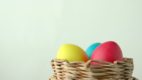 Easter decoration. Colorful festive eggs lie rotate in a basket on a white background. Easter eggs closeup.