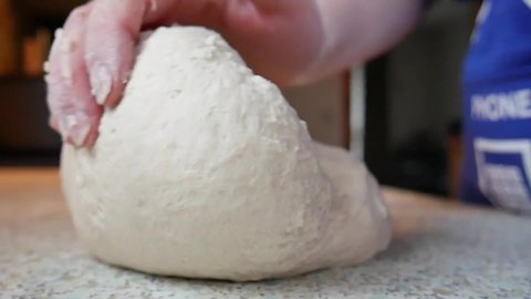 kneading sourdough bread dough on a kitchen top with hands