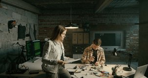 Hero Shot of Female Team Leader Working in IT Technology Electronics Startup in Loft Office in Brick Garage at Night. Woman Discusses Project and Looks at Camera. 4K Cinematic Zoom in Mid Video