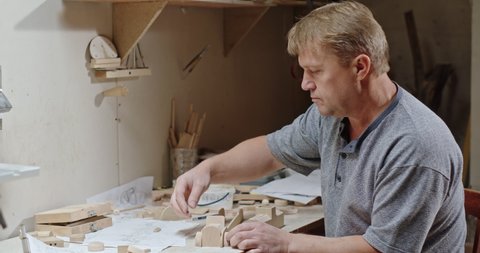 Middle aged handsome carpenter finished making wooden toy
