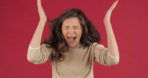 Close-up annoyed irritated young caucasian woman with angry face looking furious mad opens his mouth shouts loudly from stress feeling frustrated isolated on red studio background. Female expression