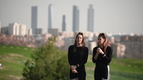 Two twin sisters walking through a green area with the city in the background - Powered by Shutterstock - Get 15% off with code: PIKWIZARD15