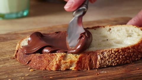 women 's hands apply chocolate nut cream on a slice of freshly baked bread close - up. home cooking breakfast zoom in