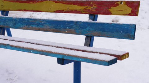Winter background with falling snowflakes on a wooden bench, winter cold, a bench for sitting covered with snow