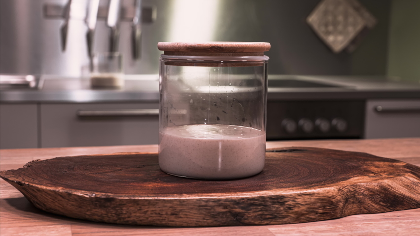 Sourdough Starter - Mixture Of Wild Yeast, Flour And Water Rising On Glass Jar With Wooden Lid During Fermentation - slider shot | Shutterstock HD Video #1067411282