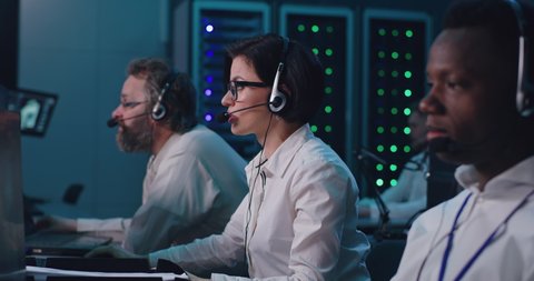 Rack focus of diverse men and women rubbing face and gesturing in frustration after mission failure in flight control center