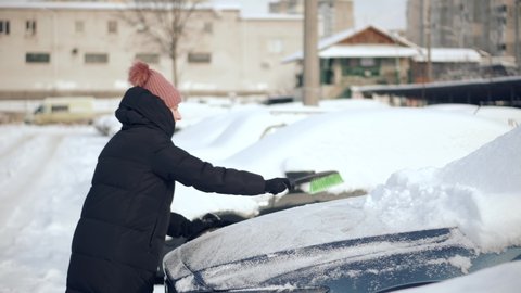 Brushing Snow And Ice From Car Glass.Female Cleaning Fresh Snow After Snowstorm From Vehicle.Sweep Snow From Automobile With Brushes In Winter.Scraping Ice From Glass.Woman Cleaning Car After Snowfall