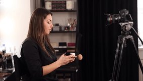 Young beautiful woman and professional beauty make up artist vlogger recording makeup tutorial in beuty studio to share on website or social media. Blogger use digital camera on tripod and ring lamp