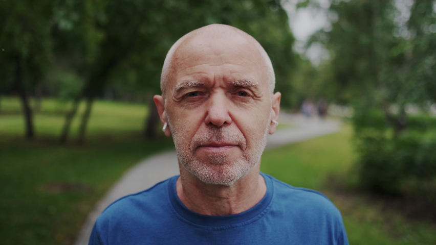 Healthy and Strong Old Man Looking in Camera and Makes Breathing Practice in Park Outdoor. Inhale and Exhale Air All Breast. Concept of Active and Positive Lifestyle. Closeup. Royalty-Free Stock Footage #1067420591