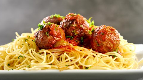 spaghetti with meatball and pouring parsley