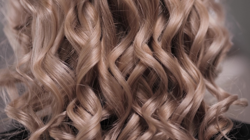 Close-up of a woman's hand combing her curled blonde hair with a red comb. Combing curly hair. High quality 4k footage | Shutterstock HD Video #1067422790