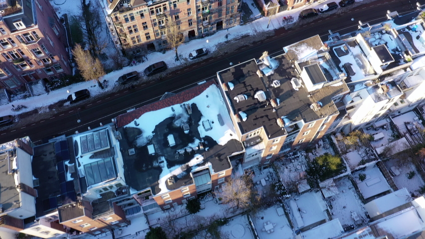 Aerial shot of houses, gardens and streets in upscale neighborhood covered in snow. Top down shot. Amsterdam, Netherlands.