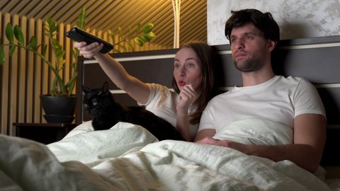 Couple watching TV at night at home lying on the bed