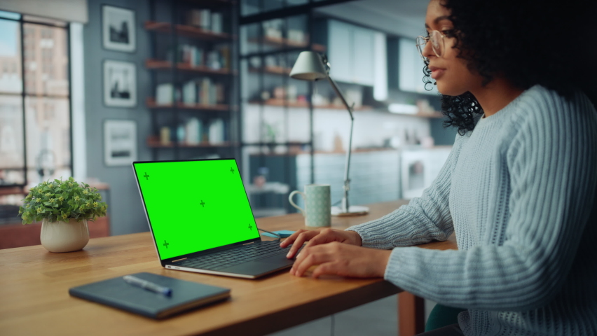 Close Up Female Specialist Working on Laptop with Green Screen Mock Up Display at Home Living Room while Sitting at a Table. Freelancer Female Chatting Over the Internet on Social Networks.