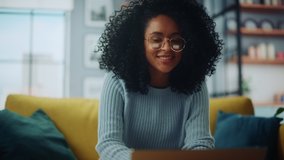 Close Up Portrait of a Beautiful Authentic Latina Female in a Cozy Living Room Using Laptop Computer at Home. She's Browsing the Internet and Checking Videos on Social Networks and Having Fun. - Powered by Shutterstock - Get 15% off with code: PIKWIZARD15