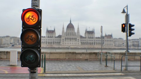 Bicycle traffic light sequence in the city of Budapest. Changing from red to green. In the background with the Hungarian Parliament Building. Cycle icon on an overcast winter (or autumn) afternoon. 4K