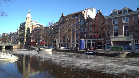 Amsterdam, the Netherlands - February 13th 2021: People ice skating on Amsterdam frozen canals. Impressive figure skating with jumps, turns and backward skating. Redaksjonell arkivvideo