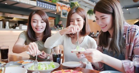 Group of asian happy friends dine together in the restaurant and they share foods to each other