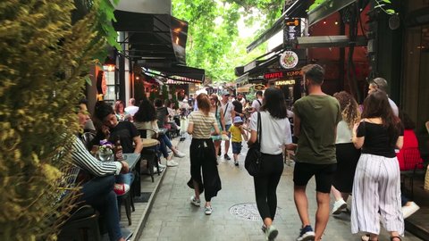 ISTANBUL - CIRCA JULY, 2019: Footage of young people walking on street, hanging out at cafes in popular neighborhood called "Karakoy" in Istanbul. It is a summer day. Camera moves forward.