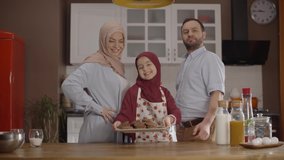 Muslim family and little girl's happiness showing proudly the cookie made by their little daughter. Family cookie concept. Slow motion video.