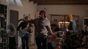 WIDE Friends playing music during their rock band rehearsal repetition inside a garage. Vocals, guitars and drums. Shot with 2x anamorphic lens - Powered by Shutterstock - Get 15% off with code: PIKWIZARD15