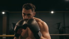 Hispanic shirtless man in boxing gloves working out on boxing ring