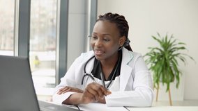 Young african american woman doctor with headset having chat or consultation on laptop