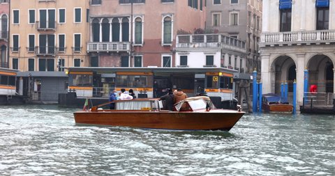 Venice, Italy - 18.11.2020: Water taxi boat passing near a gondola with people wearing antivirus masks during covid 19 pandemic on grand canal slow motion
