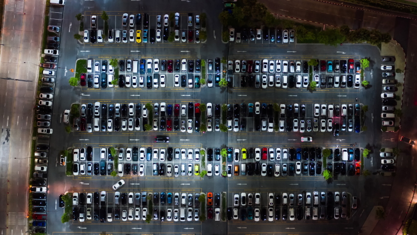 Time-lapse of car traffic, parking and leaving shopping mall's parking lot at night. Drone aerial top view, zoom out. Transportation travel, city life, or shopping people lifestyle concept | Shutterstock HD Video #1067456957