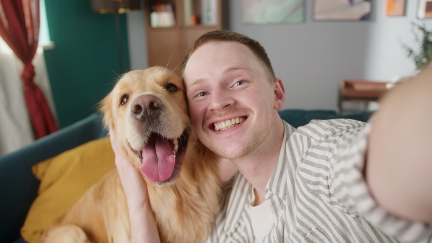 British redhead man together with dog retriever making selfie photo or video call on front camera smartphone. Positive young student man conference call with pet for blog. Royalty-Free Stock Footage #1067466344