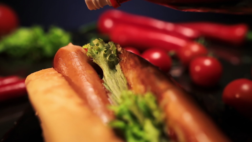 Ketchup Pouring on a Hot Dog with Sausage. Food backdrop. Tomato red ketchup close-up. Slow motion.  Royalty-Free Stock Footage #1067469227