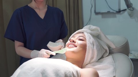 Beauty clinic doctor or nurse and carefully touch a customer woman face who lie on bed and cover hair. Business concept of beauty clinic service for beauty of skin and body. Footage B roll 4k.