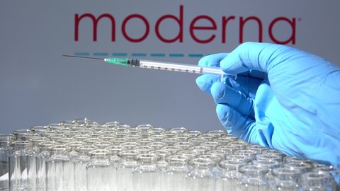 Toronto, Ontario, Canada - February 14, 2021 : A health worker prepares to administer a shot of the American vaccine Moderna. Name is blurry and vials containing messenger RNA technology vaccine.