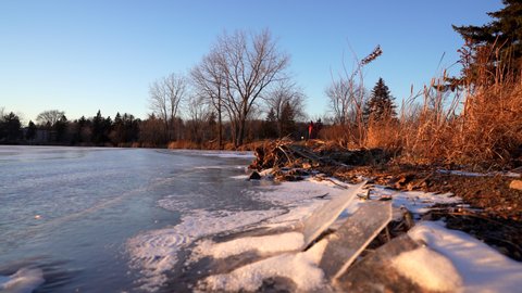 Pan shot of a frozen lake in winter by sunset