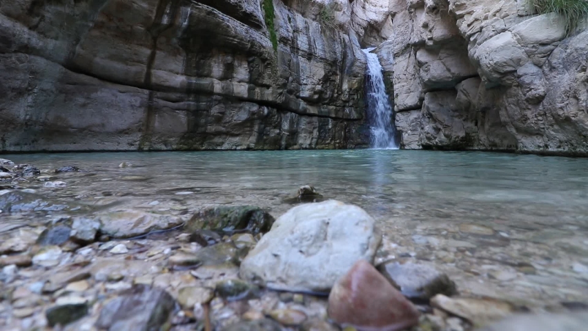 Flowing water to a large pool of clear water, in the hidden waterfall in Nahal Arugot, Ein Gedi, Israel 
