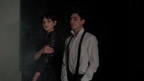 Actors posing for the camera in a dark room. Dramatic atmosphere with a little smoke. The work of photo models on the set. The video contains film grain for a retro effect.