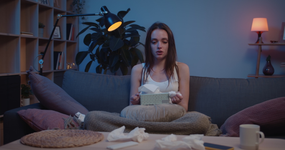 Young sad girl crying with box of handkerchief on her knees, using, crumpling and throwing them away. Unhappy millennial female using paper tissues for blowing nose and wiping tears. Royalty-Free Stock Footage #1067491139