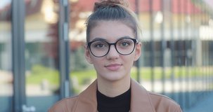 Smiling portrait of attractive woman in glasses. Confident pretty young business people. Female in down town. Growing, success concept. 4K slow motion video.