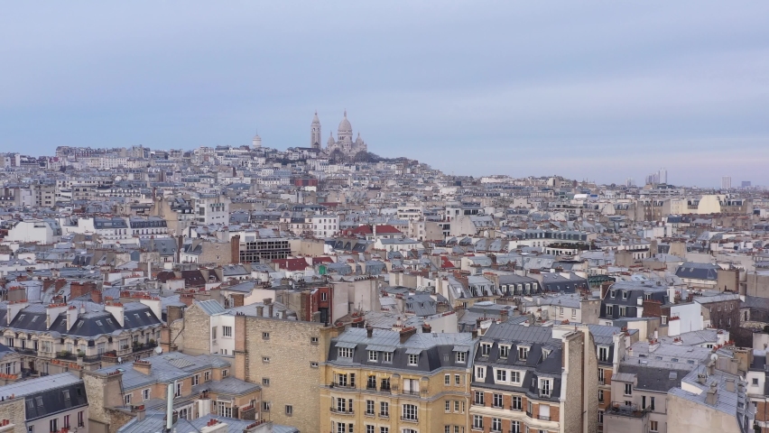 France, Paris, drone aerial view flying above buildings roofs with Sacré-Coeur Basilica church in the background. Pastel blue sky. | Shutterstock HD Video #1067494358