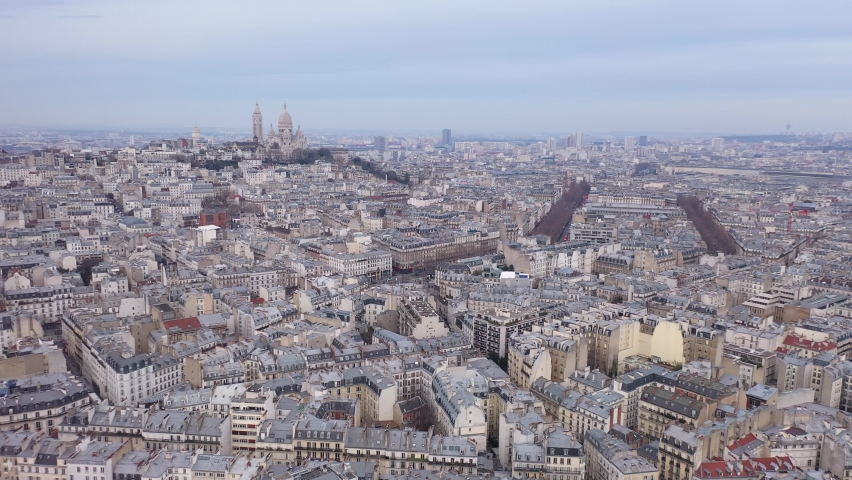 France, Paris, wide drone aerial view flying above buildings roofs with Sacré-Coeur Basilica church in the background. Pastel blue sky. | Shutterstock HD Video #1067494367