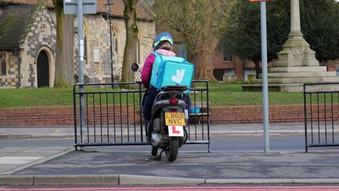 READING, UK - FEBRUARY 15, 2021: Deliveroo food delivery rider waiting for an order on a motorbike in Reading, Berkshire, UK.