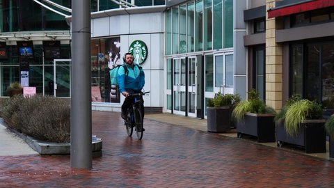 READING, UK - FEBRUARY 15, 2021: Deliveroo takeaway food delivery rider on a bicycle in Reading, Berkshire, UK.