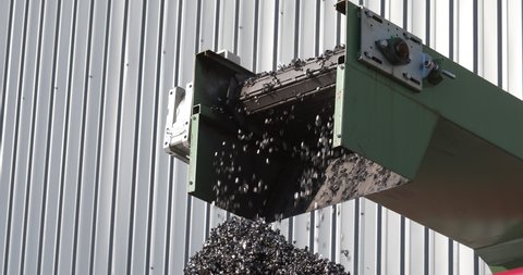 Metal pieces falling into a box from recycling processing machine. Recycled scrap metal in stock. Metal shavings production waste