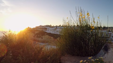 Dreamy sunset on cliffed coastlines in Carvoeiro, Portugal. With lots of housing in the distance.