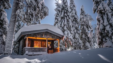 Wilderness cabin in snow covered spruce tree forest in Pyhä-Luosto National Park, Lapland, Finland, night time lapse