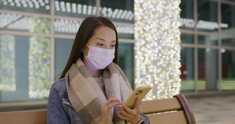 Woman wear face mask and use of smart phone at night