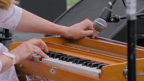 Slow motion: woman hands playing ethnic Indian classical harmonium keyboard on stage of summer open air concert - close up view. Entertainment, music, culture, leisure time and art concept