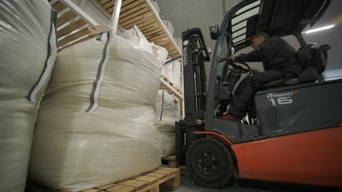 KYIV, UKRAINE - DECEMBER 2020: Warehousing. Forklift driver stacking big bag of raw material in warehouse. Many bags of raw materials in the warehouse